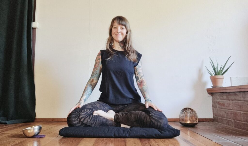 Angelina Katharina Petersen, sitzt auf ihrem Meditationskissen und ist ausgebildete Meditationslehrerin in Leipzig
