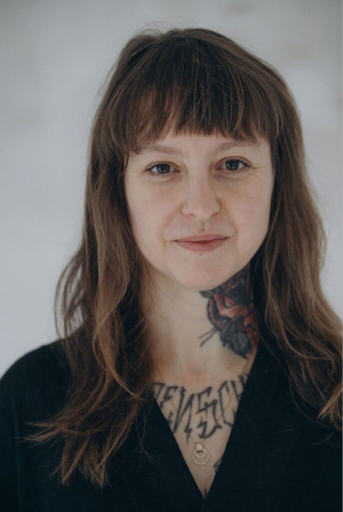 Angelina Katharina Petersen, Potrait. Schaut den Betrachter direkt, bestimmt und freundlich an. Sie sagt: ich sehe dich. Sie begleitet Menschen hin zu innere Ruhe und Klarheit in Leipzig