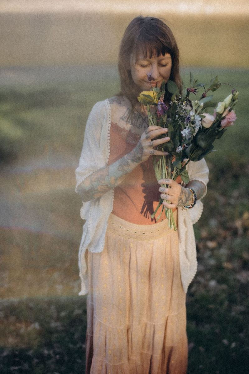 Angelina Katharina in der Natur, mit einem Strauß Blumen, Sie begleitet Menschen als spirituelle coachin in leipzig